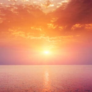 A sunset over the ocean with clouds in the sky.